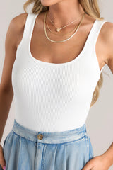 Close up view of this bodysuit that features a scoop neckline, an open back, a ribbed material, and snap button closures at the bottom.