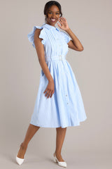 Side view of this dress that features a collared neckline, ruffle sleeves, a full button front, pleated details throughout the front, belt loops, an adjustable belt with a functional buckle, and hip pockets.
