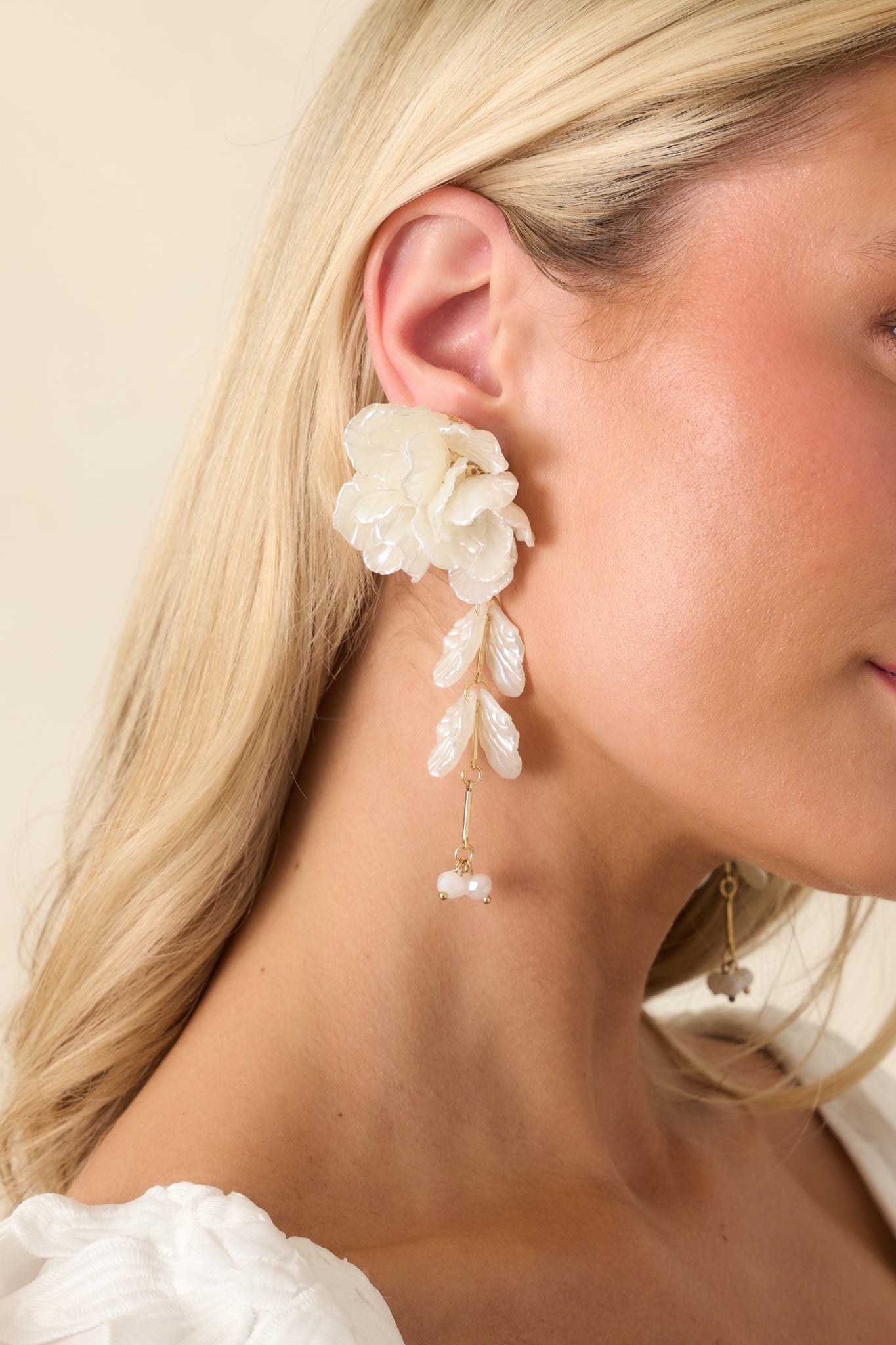 Cropped front view of ivory drop earrings with a sculpted floral stud and cascading petal accents.