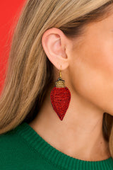 Model shown wearing earrings that feature beaded light bulbs, gold detailing, and fish hook fastening