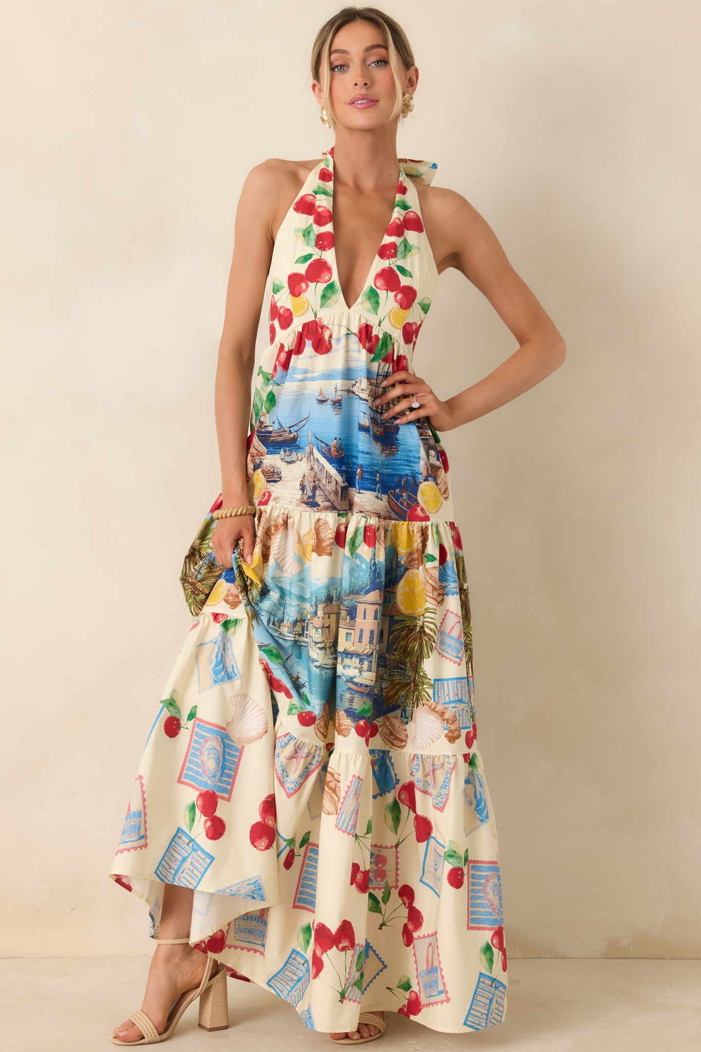 Vibrant halter dress with a flowing tiered skirt, tie-back neckline, and colorful Mediterranean-inspired prints including citrus and coastal scenes.