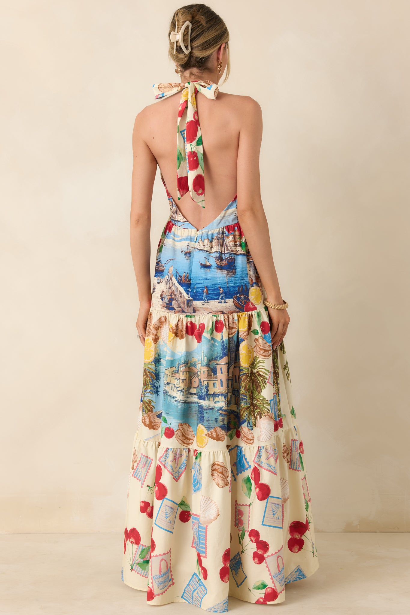 Rear view of the multi-print halter dress featuring an open back design, adjustable tie-back neckline, and flowing tiered skirt silhouette.

