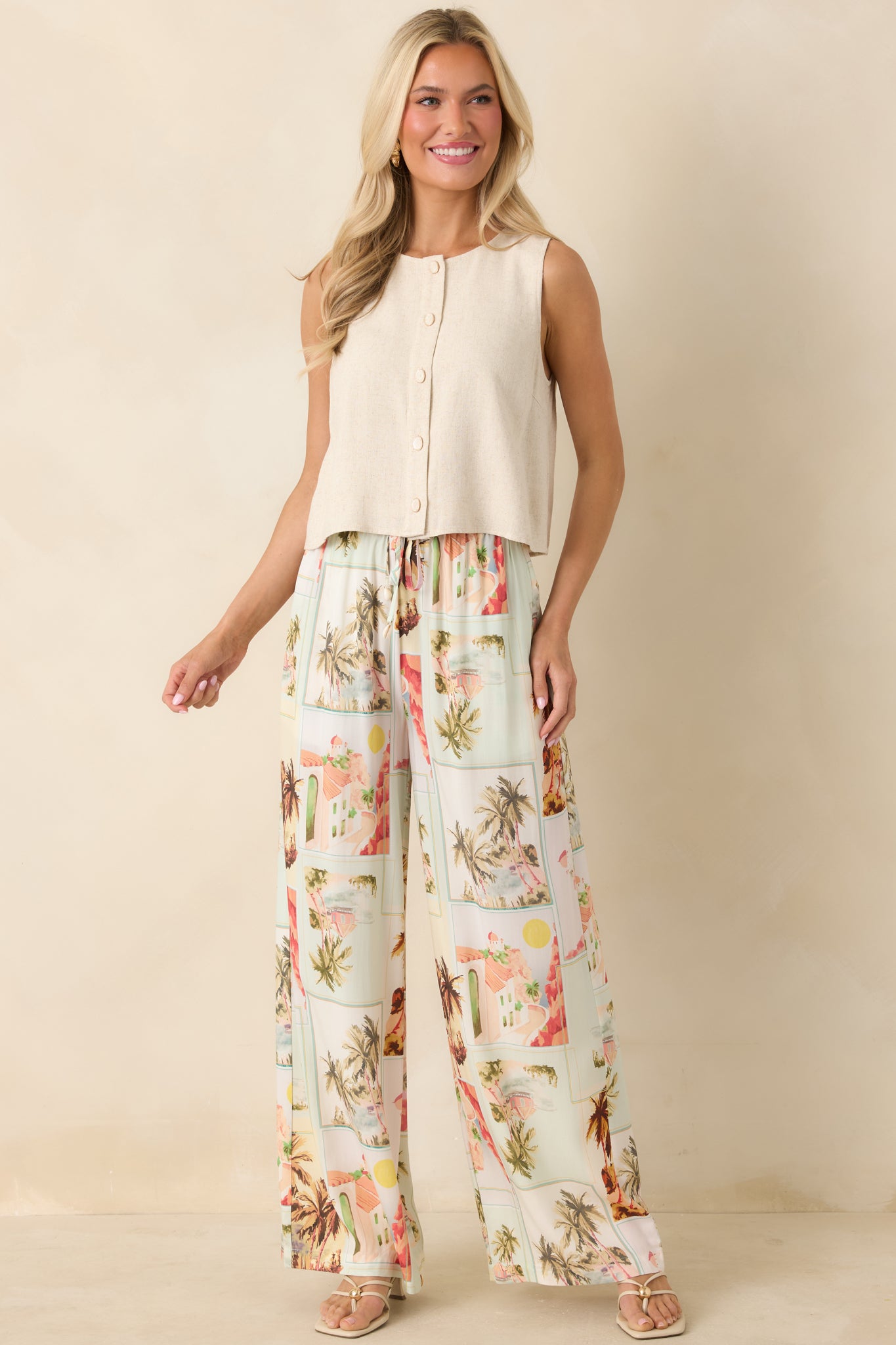 Wide-leg drawstring pants in a vintage postcard print with palm trees and sun-faded hues, featuring a relaxed, flowy silhouette