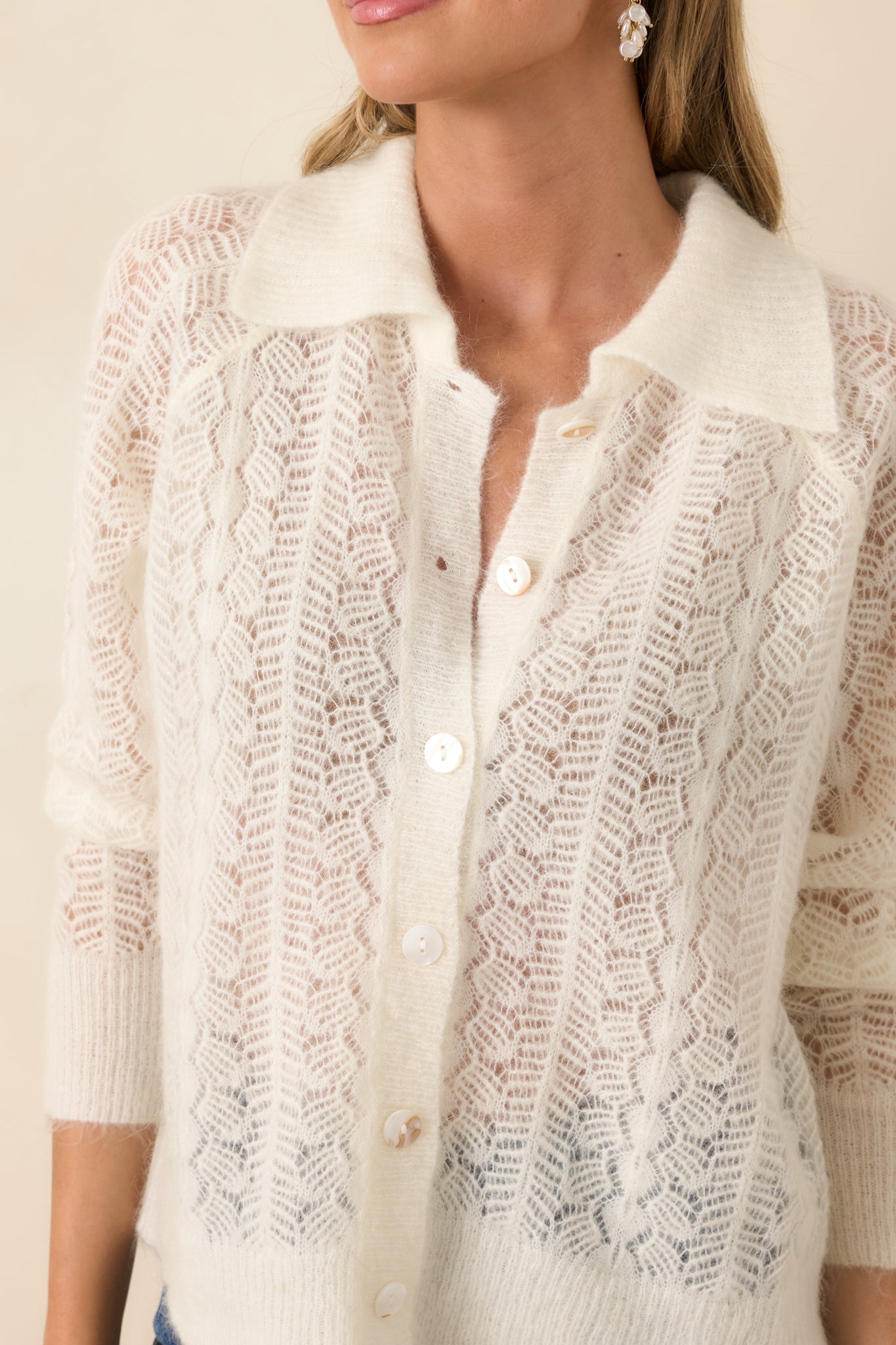 Close-up of chevron openwork knit and mother-of-pearl buttons.