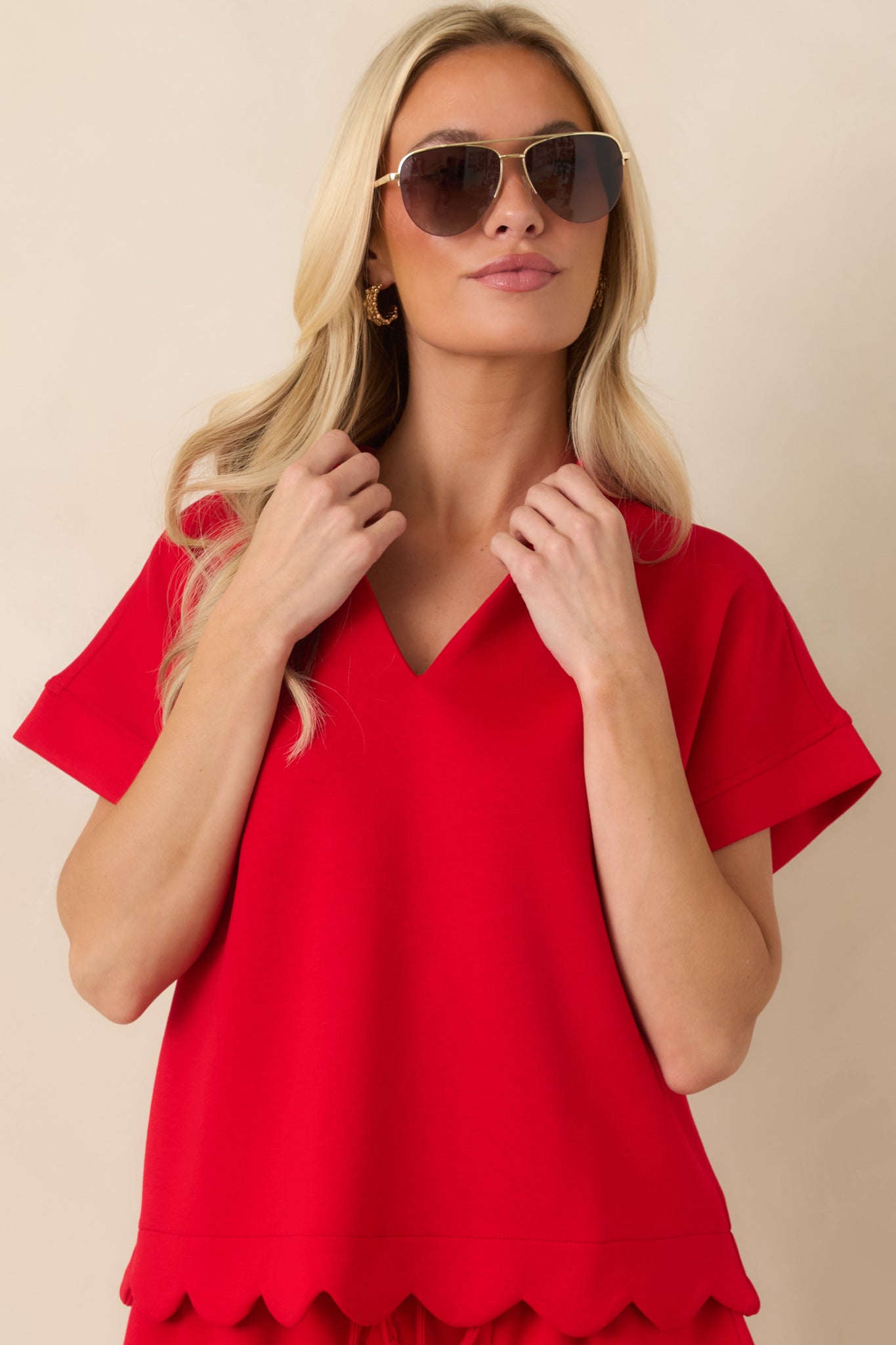 Red top with a relaxed shape and scalloped hemline shown in a detailed front view.