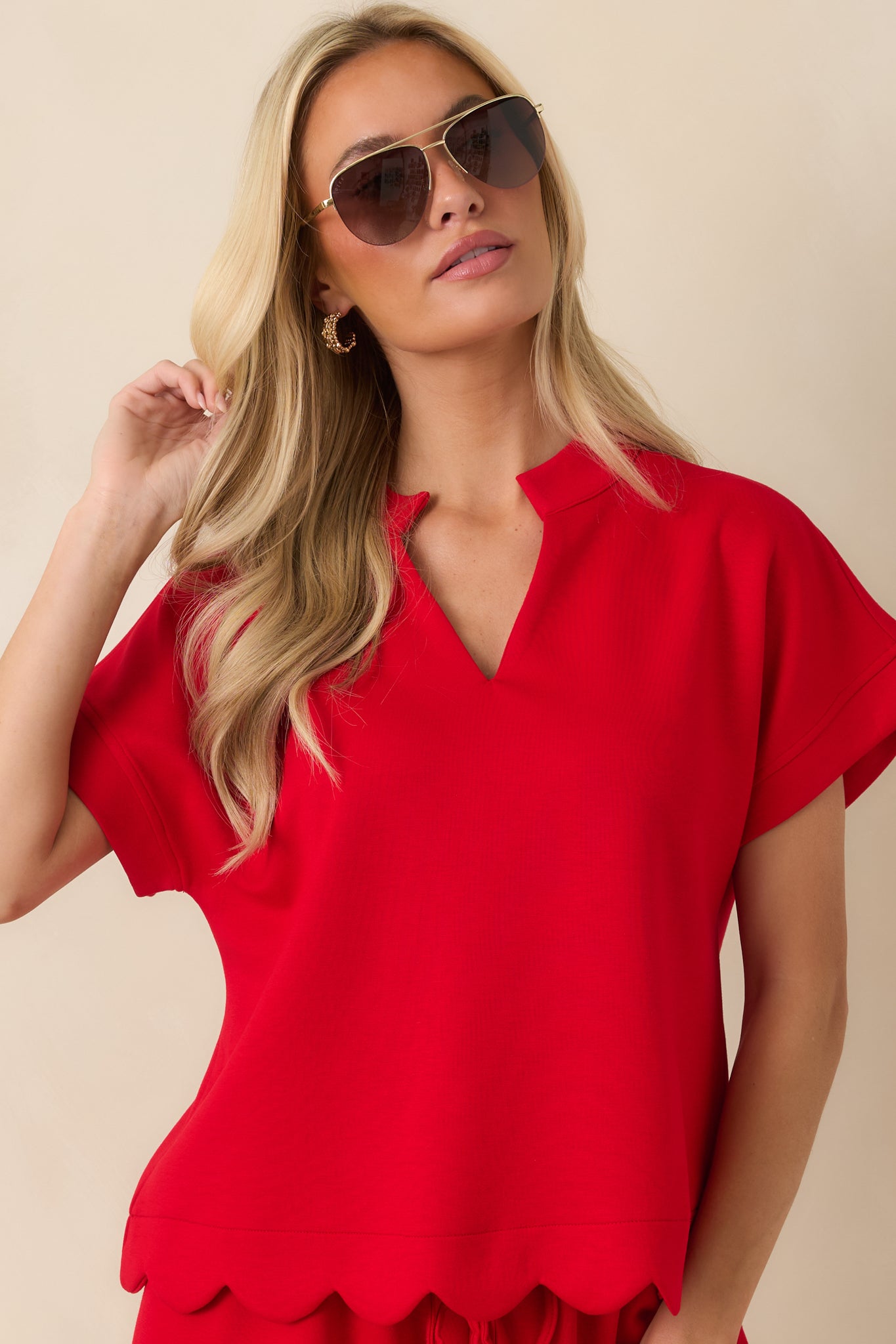 Cropped detail of the red blouse featuring cuffed short sleeves and structured fabric.