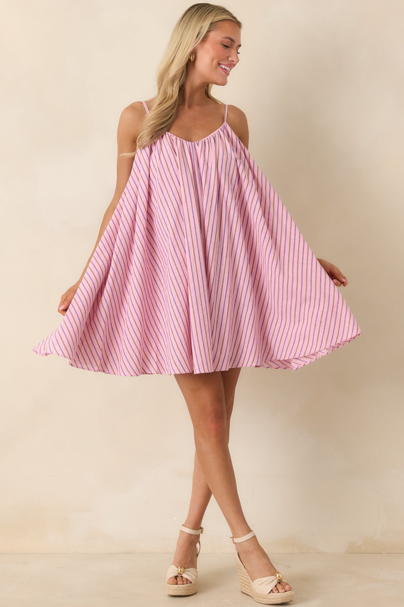 Pink striped mini dress with airy swing silhouette, spaghetti straps, and relaxed drape.