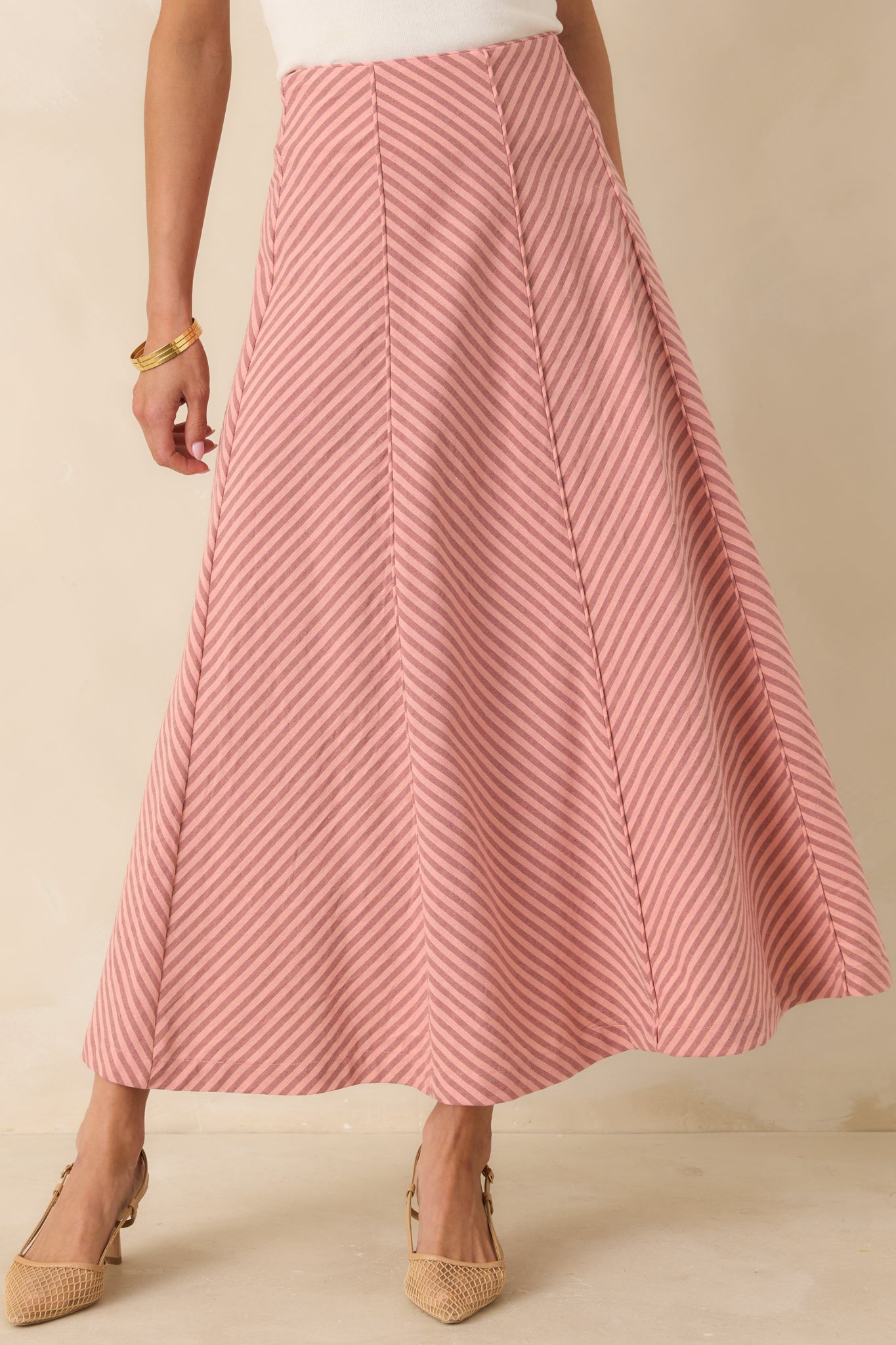 Cropped view of coral pink stripe midi skirt highlighting the high-rise waistband and panel seam details.