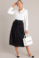 Full body view of a black skirt featuring a high-waisted fit, an elastic waistband, shiny material, and a pleated design.