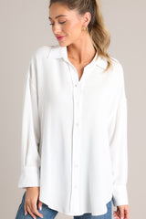 Full front view of this top that features a collared neckline, dropped shoulders, functional buttons down the front, and buttoned cuffed long sleeves.