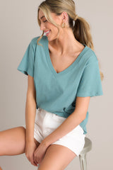 Angled view of this green top that features a v-neckline, short sleeves, and a lightweight fabric.