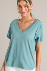 Front view of this green top that features a v-neckline, short sleeves, and a lightweight fabric.