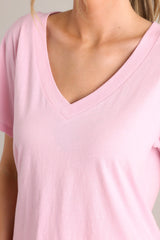Close up of this blush pink top with a graceful v-neckline, short sleeves, and crafted from a breathable lightweight fabric.