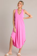 This pink dress features a v-neckline, a seam down the front and back, a soft lightweight material, and a scoop hemline.