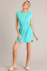 Full body view of this green dress that features a crew neckline, smocking in the waist, a textured material, and a vibrant color.