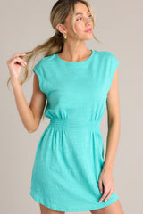 Front view of this dress that features a crew neckline, smocking in the waist, a textured material, and a vibrant color.