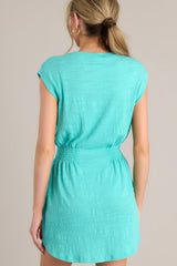 Back view of this dress that features a crew neckline, smocking in the waist, a textured material, and a vibrant color.