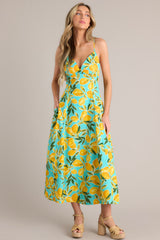 This aqua midi dress features a v-neckline, thin adjustable straps with a self-tie feature, an open back with functional buttons, functional hip pockets, and, a vibrant aqua lemon print.