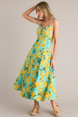 Side view of this aqua midi dress that features a v-neckline, thin adjustable straps with a self-tie feature, an open back with functional buttons, functional hip pockets, and, a vibrant aqua lemon print.