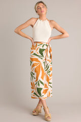 Full body view of this tropical print midi skirt that features a high waisted design, an elastic waist insert, self-tie wrap features, an orange & green tropical print, and a lightweight fabric.