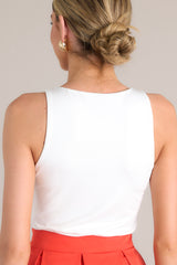 Back view of this white bodysuit that features a high neckline, stretchy fabric, a snap button closure, and a thong style bottom