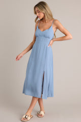 Side view of this ash blue midi dress that features a v-neckline, thin adjustable straps, a smocked back insert, gathering in the bust, a thick waistband, and a side slit.