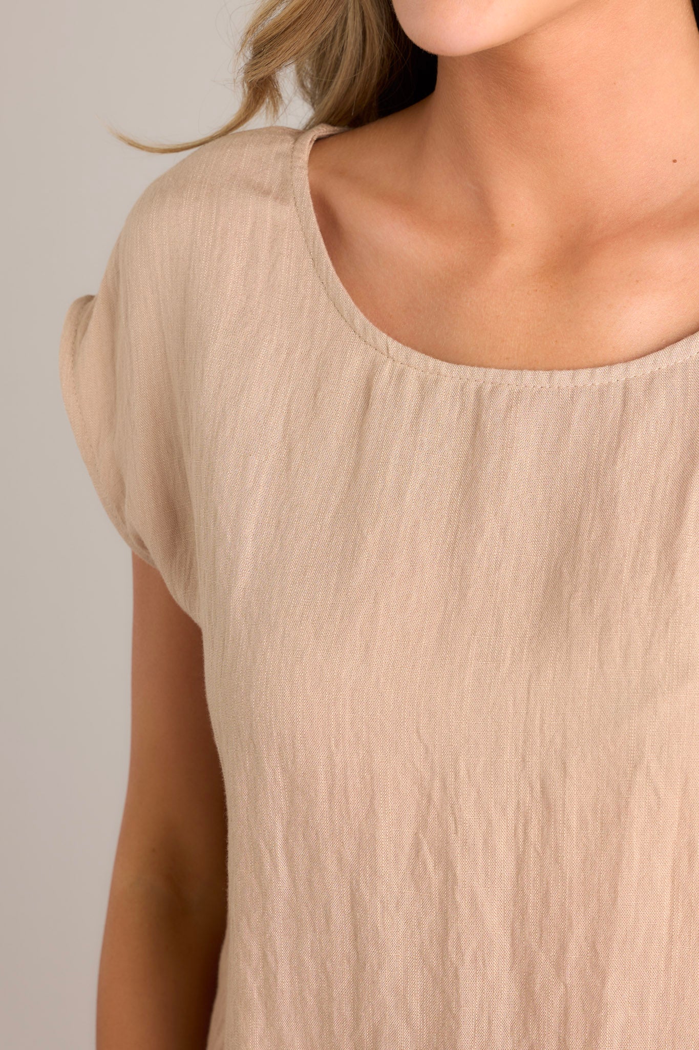 Close up view of this top that features a cap sleeve design, a crew neckline, slightly cropped length, and breezy lightweight fabric. 
