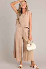 These tan pants feature an elastic waistband, functional pockets, a cropped length, and a lightweight fabric.