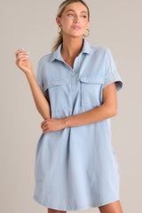 Close up front view of this light chambray mini dress that features a collared neckline, functional breast & hip pockets, a relaxed fit, and cuffed short sleeves.