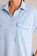 Close-up of a light blue denim mini dress with a collar and two chest pockets.