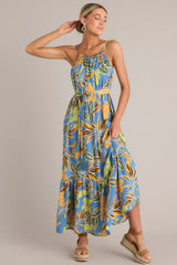 Full body view of this dusty blue maxi dress that features an elastic scoop neckline, thin adjustable straps, a self-tie feature in the back, gathering in the bust, a self-tie waist belt, a single tier, and a flowing silhouette