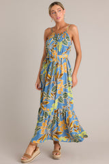 Side view of this dusty blue maxi dress that features an elastic scoop neckline, thin adjustable straps, a self-tie feature in the back, gathering in the bust, a self-tie waist belt, a single tier, and a flowing silhouette