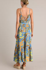 Back view of this dusty blue maxi dress that features an elastic scoop neckline, thin adjustable straps, a self-tie feature in the back, gathering in the bust, a self-tie waist belt, a single tier, and a flowing silhouette