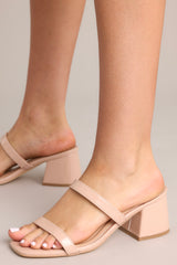 Close up view of these nude block heels that feature a square toe, two nude straps across the top of the foot, and a block heel.