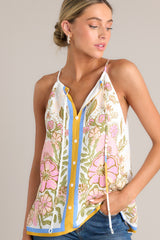 Close up side view of this  ivory tank top with a v-neckline featuring a self-tie feature, thin straps, a faux button front, and a unique floral pattern.