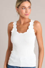 Angled front view of this ivory tank top with a scalloped scoop neckline, thick scalloped straps, ribbed texture, and a bodycon fit