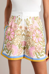 Close up view of these Ivory high-waisted shorts with an elastic waist insert, hook & bar with zipper closure, functional hip pockets, and a unique floral print