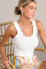 ivory tank top with a scalloped scoop neckline, thick scalloped straps, ribbed texture, and a bodycon fit