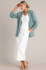 Angled full body view of this forest green blazer with a folded neckline, shoulder padding, faux pockets, and gathered quarter-length sleeves.