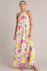 Front view of this dress with self-tie halter neckline, additional thin adjustable straps, open back, self-tie waist belt, and flowing silhouette, adorned with a multi-floral print.