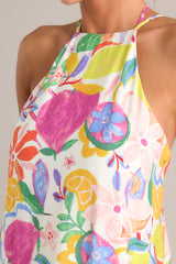 Close up view of dress with self-tie halter neckline, additional thin adjustable straps, open back, self-tie waist belt, and flowing silhouette, adorned with a multi-floral print.