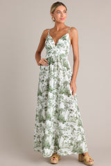 Full body angled view of this green toile maxi dress that features a v-neckline, thin adjustable straps, a slightly pleated bust, a smocked back insert, a thick waistband, and a flowing silhouette.