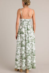 Back view of this green toile maxi dress that features a v-neckline, thin adjustable straps, a slightly pleated bust, a smocked back insert, a thick waistband, and a flowing silhouette.