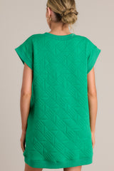 Back view of this green mini dress that features a v-neckline, an all over quilted design, functional hip pockets, and flattering cap sleeves.