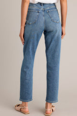 Back view of these high-waisted jeans featuring a traditional button and zipper closure, complete with functional belt loops and pockets for added convenience.