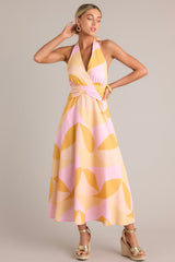 Front view of this light pink & orange  features a self-tie halter neckline, open back, thick waistband, discrete back zipper, and flowing silhouette.