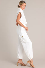 Side view of this jumpsuit that features a collared neckline, a half button front, an adjustable self-tie waist feature, buttoned utility pockets, self-tie cuffed ankles, and folded short sleeves.