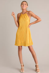 This goldenrod mini dress features a self-tie halter neckline, an elastic band in the back, and an all over ribbed texture.