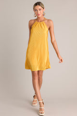 Full body view of this goldenrod mini dress that features a self-tie halter neckline, an elastic band in the back, and an all over ribbed texture.