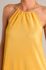 Close up view of this goldenrod mini dress that features a self-tie halter neckline, an elastic band in the back, and an all over ribbed texture.